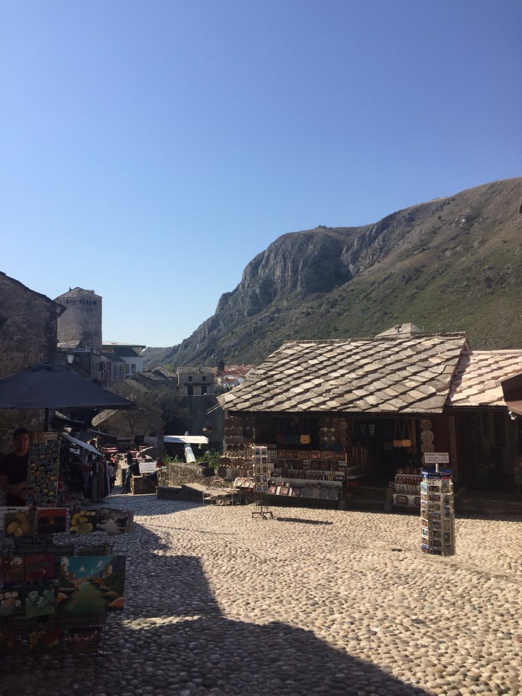 The entrance to the old market with cobbled flooring, stalls and the mountains in the backgroun