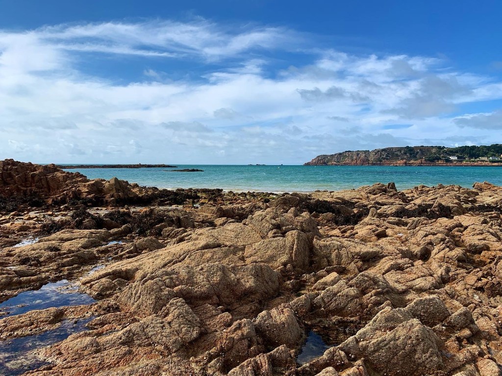 St Brelades Bay in Jersey on the rocks with blue skies and sea